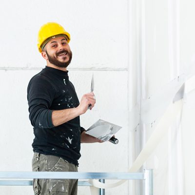 Interior construction, worker plastering gypsum board wall.