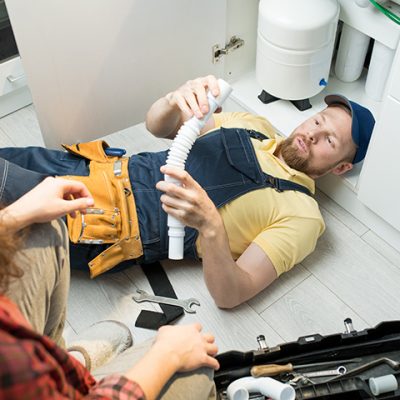 Young plumber changing trap under sink